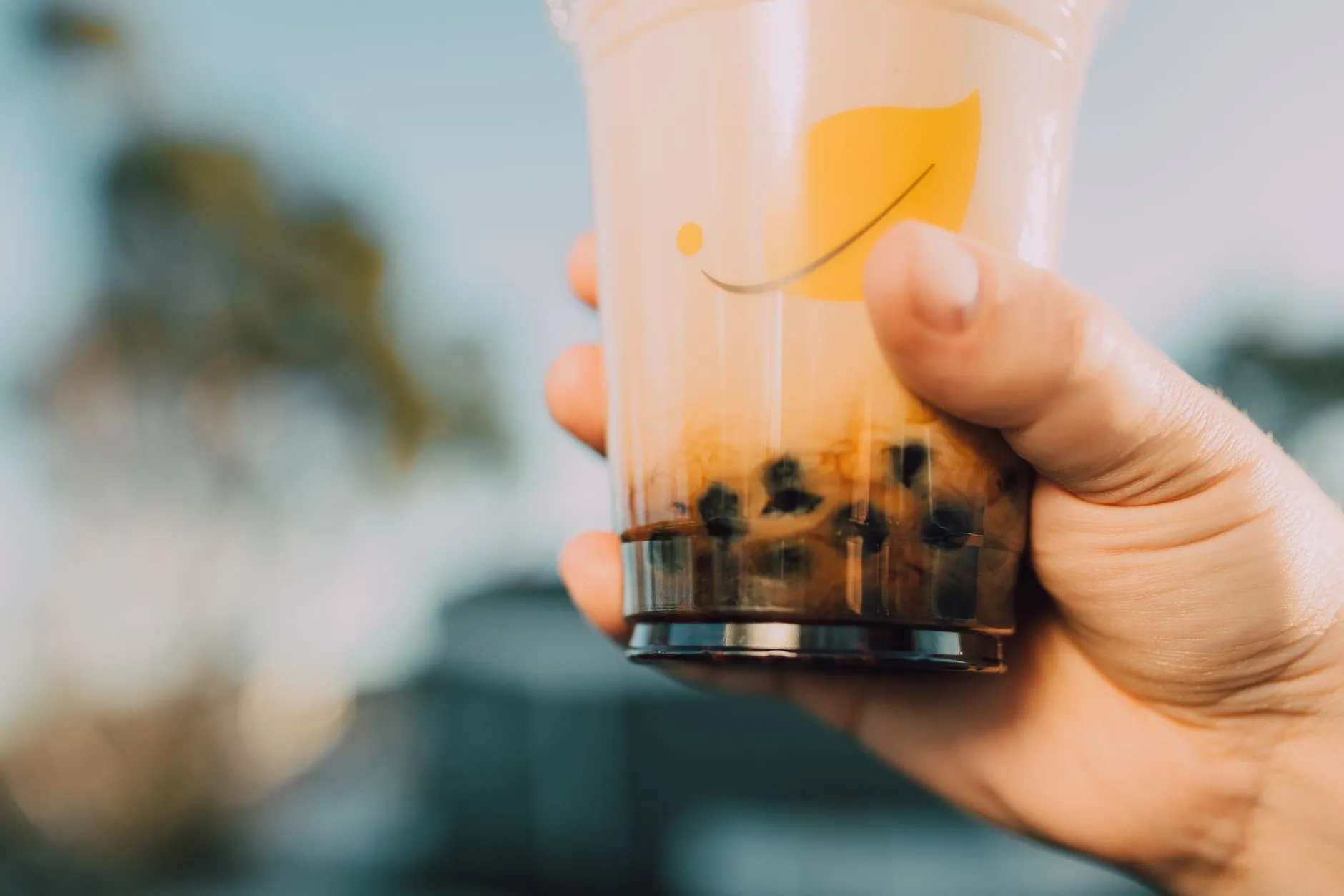 יד מחזיקה כוס בועות תה (bubble tea) עם רקע מטושטש